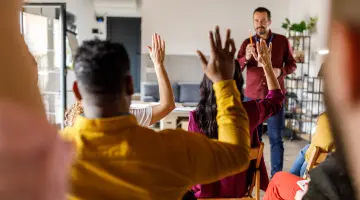 Fragen und Antworten: Gruppe von Personen, die ihre Hände heben, um bei einer Veranstaltung Fragen zu stellen.