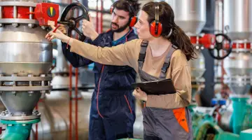 Ingenieurin und Ingenieur warten gemeinsam ein Ventil an einer Gasleitung in einem Erdgasspeicher.