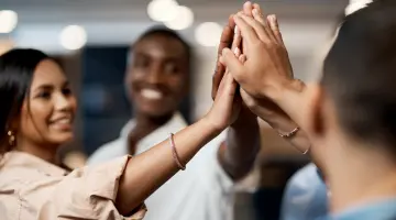Handschlag zur Begrüßung: Multiethnische Gruppe von Frauen und Männern begrüßt sich mit High Five.