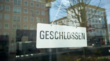 An der Eingangstür eines Unternehmens hängt ein Schild mit der Aufschrift "Geschlossen".